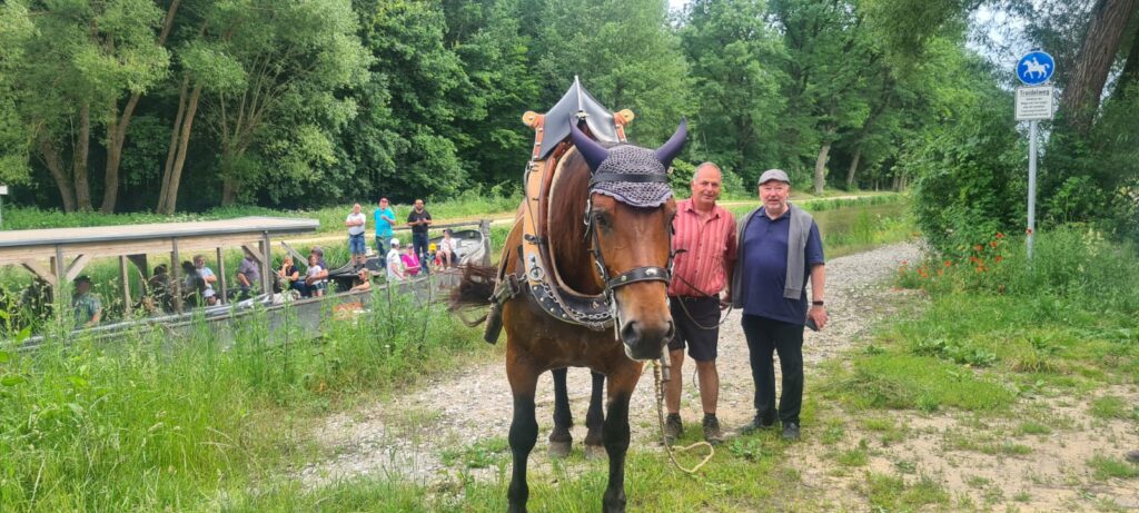 Abbildung: Kutscher-Alm Chef Martin Deflorin zusammen mit dem Geschäftsführer der Schiffshebewerks-Tourismus Jan Mönikes (rechts) und einer 6-jährigen süddeutschen Kaltblut-Stute, die regelmäßig den historischen Treidelkahn „Alma Victoria“ über den Ludwig-Donau-Main-Kanal bei Berching treidelt.