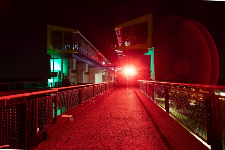 Farbig ausgeleuchteter Zugang zum Hebewerk bei Nacht.